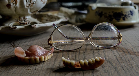 Dentures sitting out on table with glasses behind them