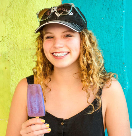 Woman with black tank top smiling while holding a popsicle