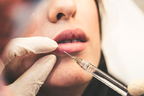 Women recieving a botox injection in lower lip