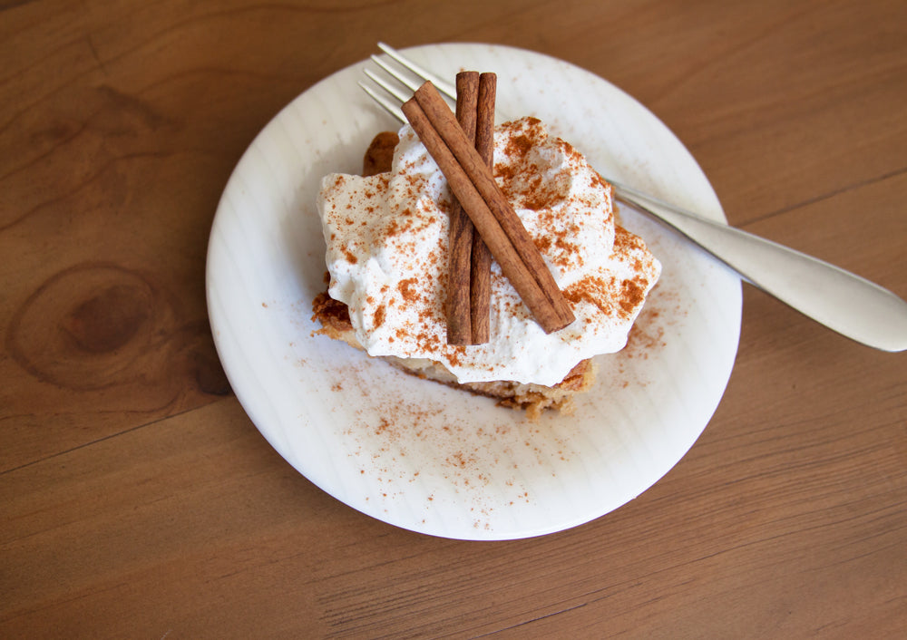 Slice of Apple Pie Cake topped with whipped cream and cinnamon