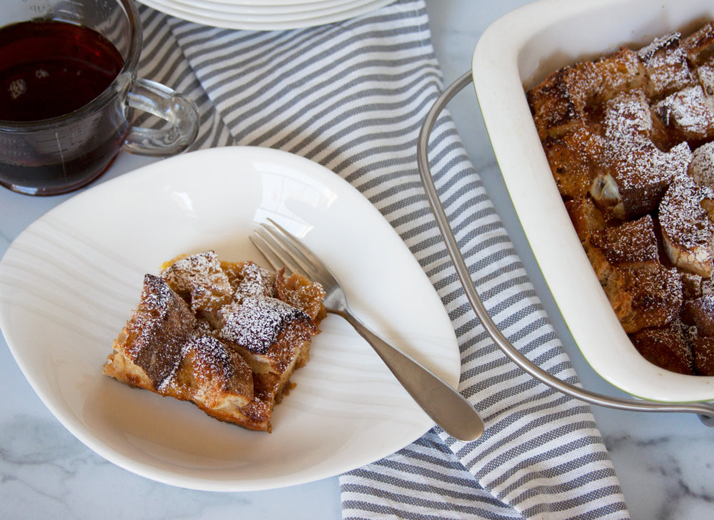 Make ahead French toast casserole topped with powdered sugar with a side of maple syrup