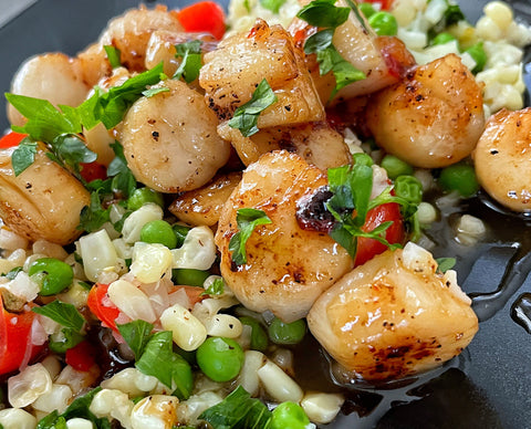 Pan seared scalloped with a medley of buttered vegetables topped with a hot peach and honey sesame glaze