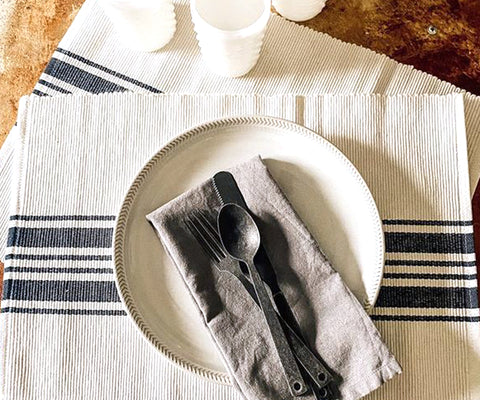 Navy blue striped placemats add a nautical touch to the table setting, pairing effortlessly with crisp white plates and silver utensils. The subtle stripes evoke a sense of seaside charm and timeless elegance.