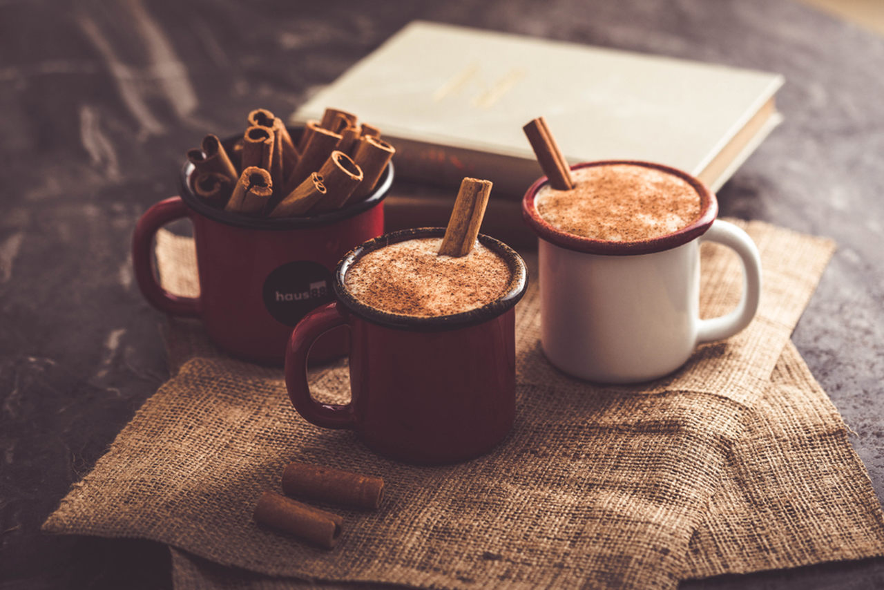 salep nasıl yapılır sorusunun yanıtı niteliğinde iki emaye fincan dolusu bol köpüklü ve tarçınlı salep ve yanlarındaki bir fincan içinde duran rulo tarçınlar