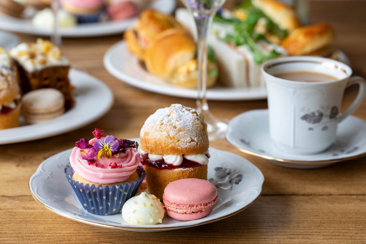 bir fincan kahvenin yanında makaron ve cupcakeli tatlı tabağı