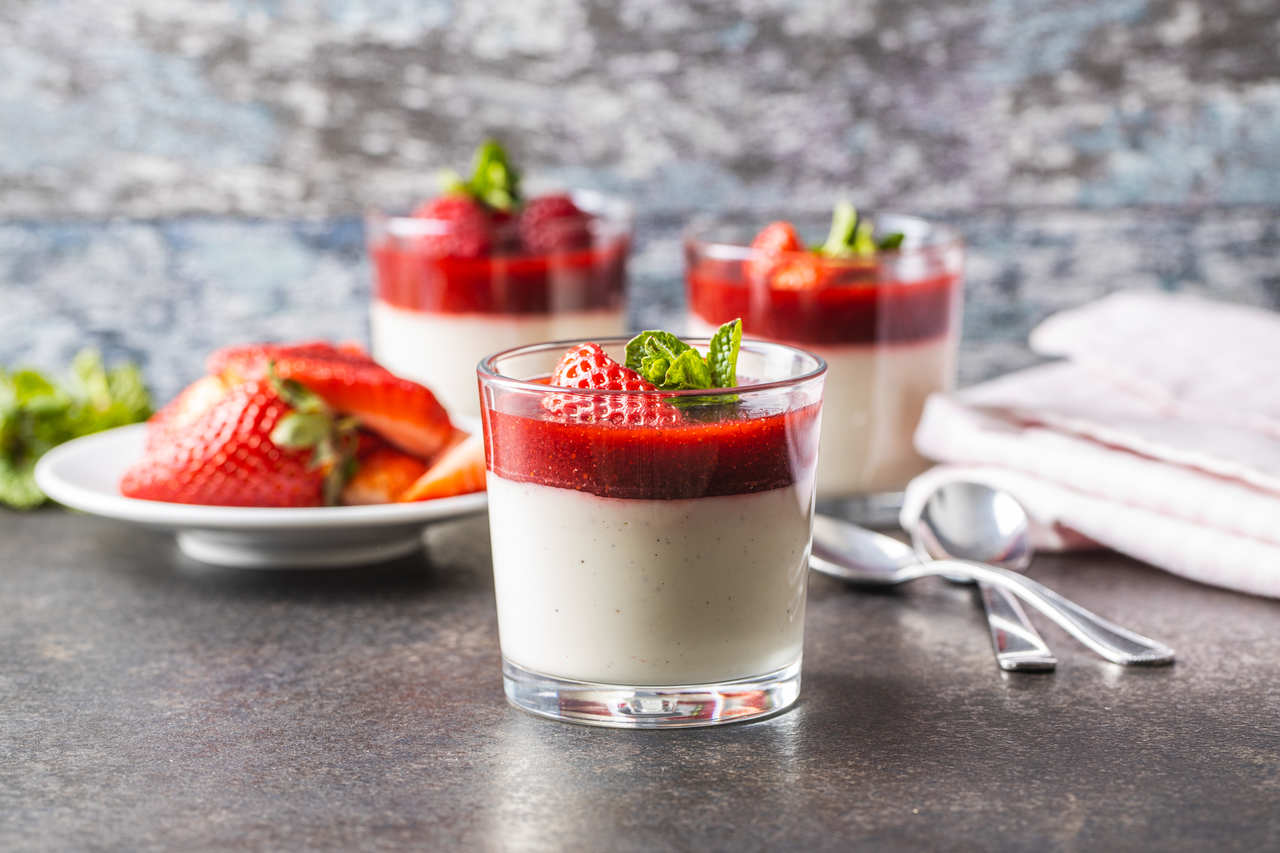 bir masanın üzerinde duran çilekli panna cotta'lar