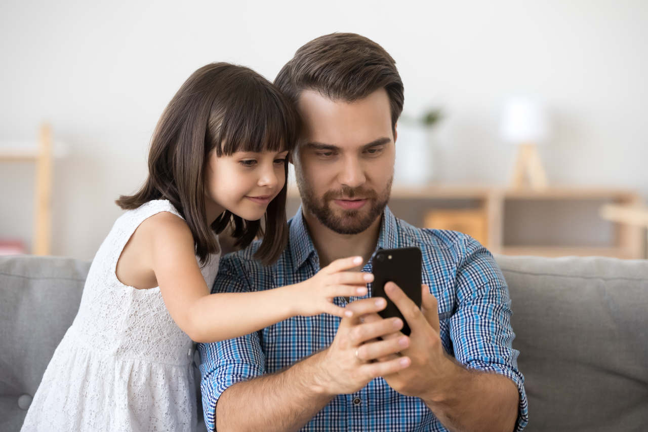 telefon ekranına bakan baba ve kız