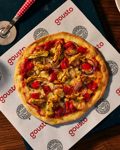 Image of a whole pizza sitting on top of a sheet of branded greaseproof paper featuring joint branding with Pizza Express and Gousto