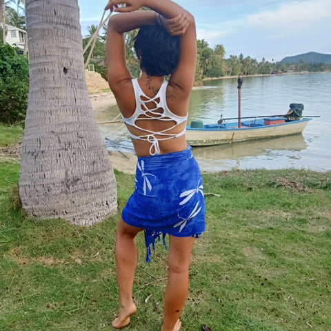 Blue sarong with white batik pattern worn as a wrap around mini skirt paired with Snow Goddess Top by Lotus Tribe Clothing. 