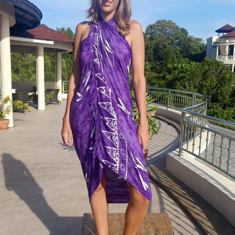Purple tie dye rayon sarong with white batik dragonfly pattern worn as a wrap around dress tied behind her neck. 