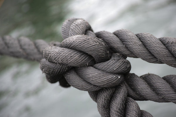 Jack Dusty Clothing & Lifestyle blog - Heavy weathered rope tied in a big knot in focus and the sea in the background.