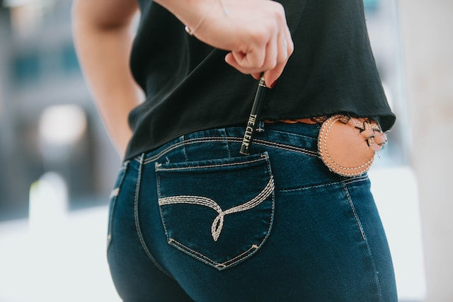 woman holding a vape in her back pocket