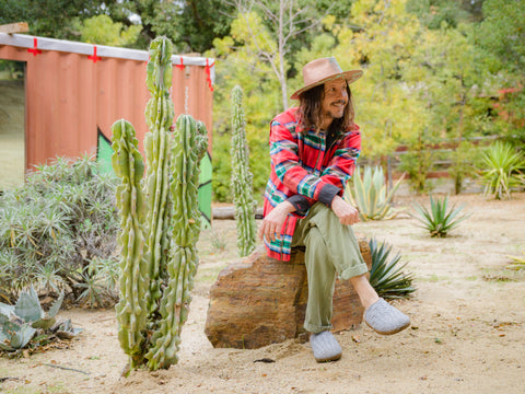 Photo Cisco Adler sitting down wearing Malibu Sandals Felt Closed toe Colony with Red flannel and Hat for Locals Local segment. 