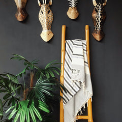 Striped towel hanging on bamboo rack with green plants and wall decor