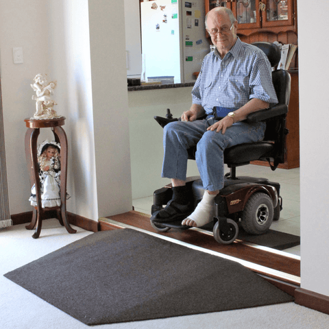 Heeve Recycled Rubber Wheelchair Threshold Door Ramp on an internal house step with a man in a mobility scooter about to go down the ramp smiling