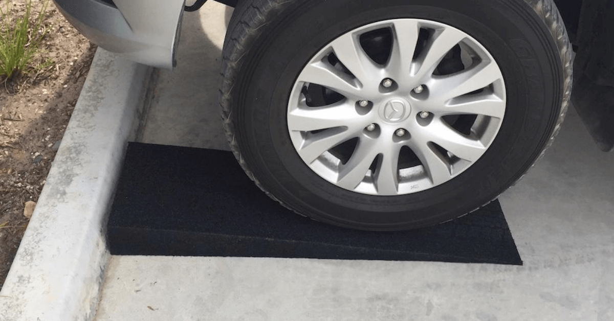 Phot of a black solid rubber kerb ramp installed on a square driveway