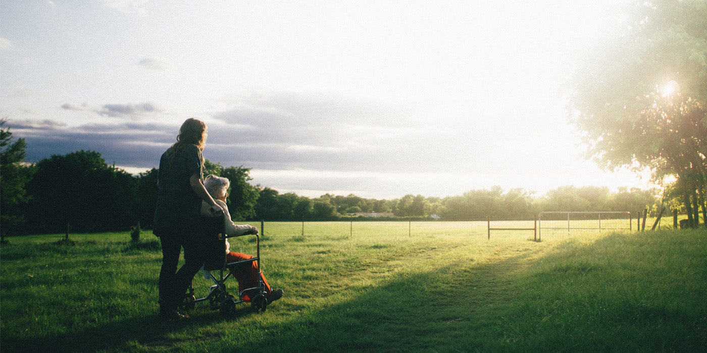 woman standing next to woman riding wheelchair