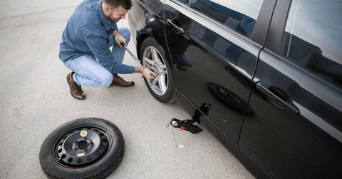 Image of a man replacing a car's flat tyre