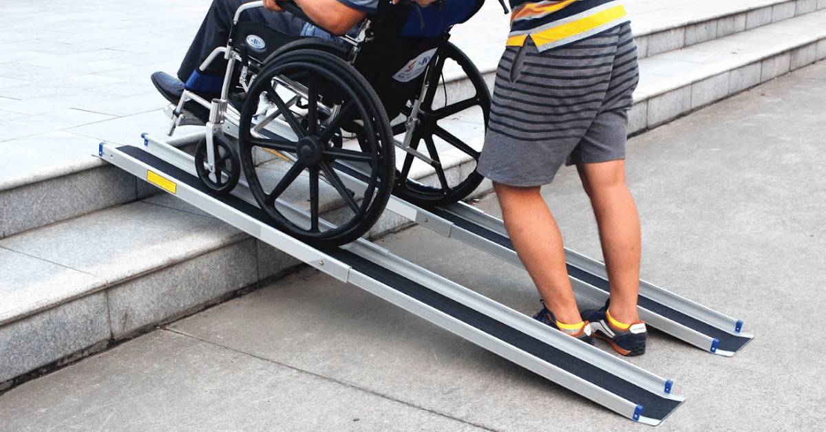 man pushing a man on wheelchair using a pair of wheelchair ramps