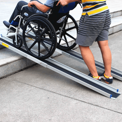Heeve Lightweight Telescopic Wheelchair Ramps & Carry Bag  being used by a man pushing another man in a wheelchair up concrete steps outside