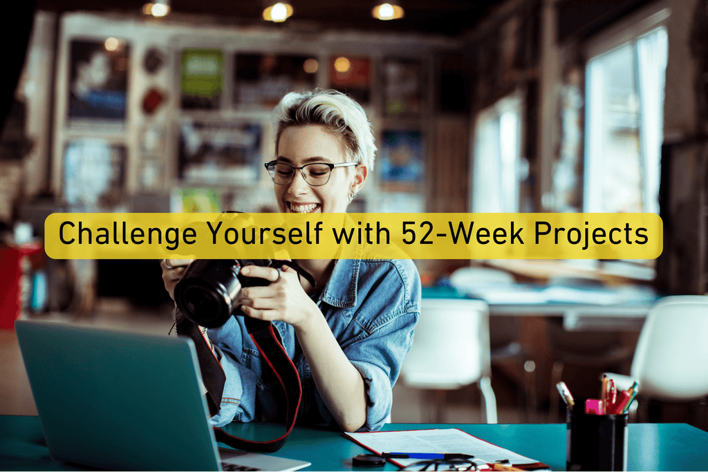 photographer holding a pro camera and sitting next to a laptop with Challenge Yourself with 52-Week Projects text overlay