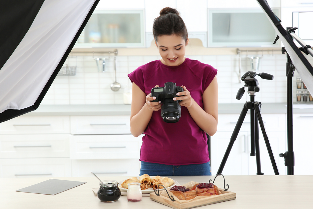 Lady taking photos of food next to different light modifiers
