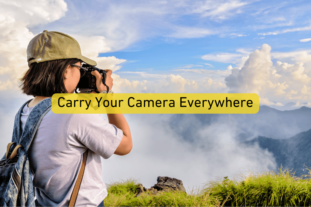 female photographer taking a picture of a landscape with Carry Your Camera Everywhere text overlay