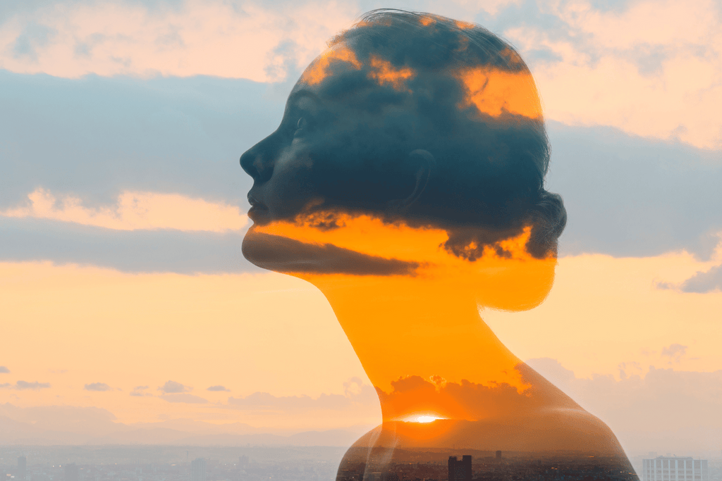 double exposure photo of a woman's head in the clouds at sunset
