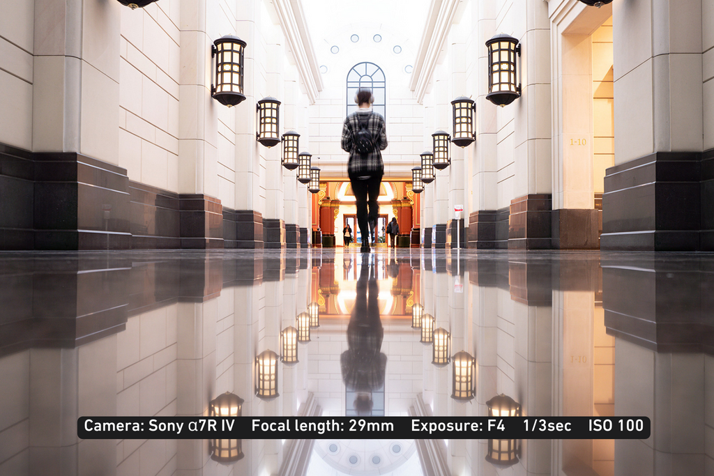 slow shutter photo of a person walking inside a marble hallway