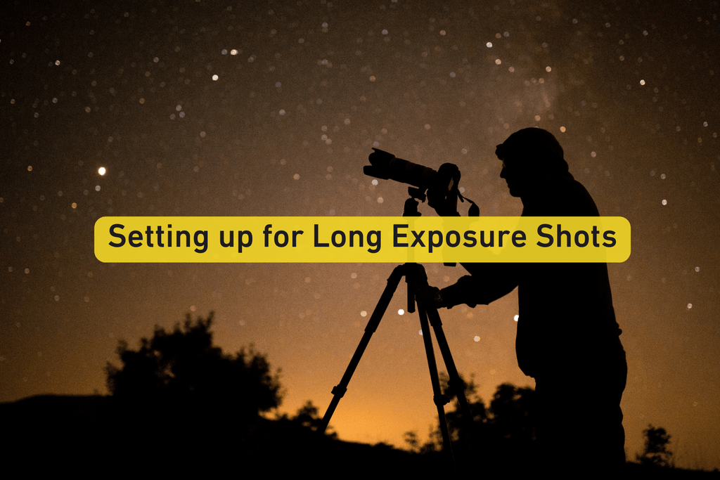 photographer holding a tripod with a camera and long zoom lens attached to it at night