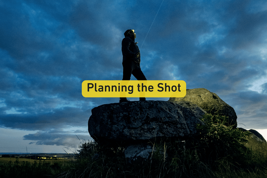 photographer standing on top of a rock at night