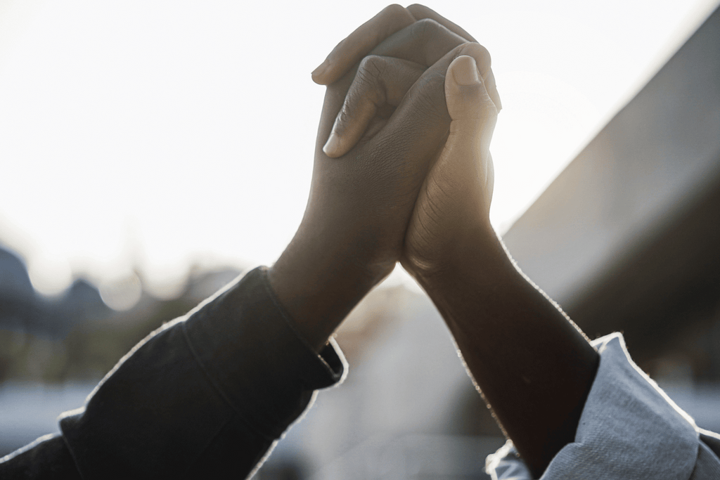 close up photo of two ethnics hands interlocking together in mid air