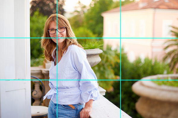 Woman standing in a balcony and smiling at the camera, rule of thirds overlay