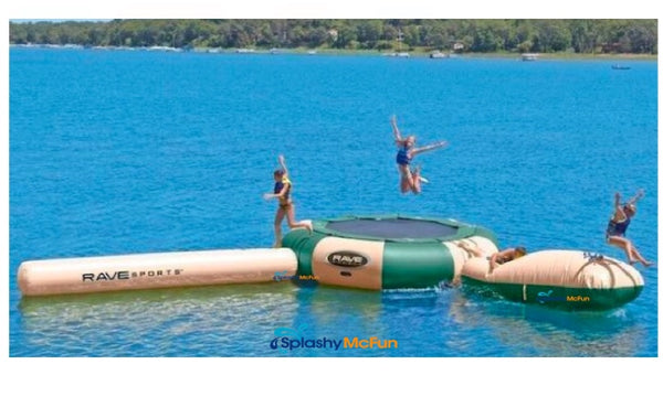 A tan and green water trampolines sit on a lake while 2 kids jump on it.