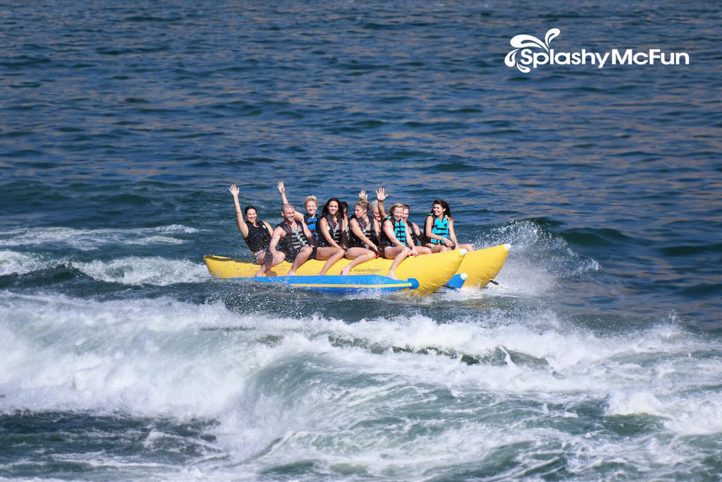This is the Island Hopper 10-Person Banana Boat Tube on the water with 10 people on it waving at the camera.