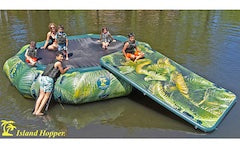5 kids and an adult relax on the Lakeside Water Bouncer with the Lakeside Water Mat attached on the side. The water bouncer is green with green leave shapes on the side