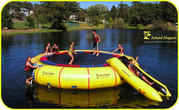 Island Hopper 25ft Giant Jump Water Trampoline is played on by 7 kids. Bounce n slide trampoline attachment is also in use.