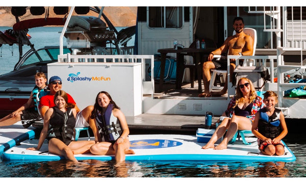 6 people sit on an inflatable dock connected to a houseboat. They sit steady in chairs with a cooler also on the inflatable dock.