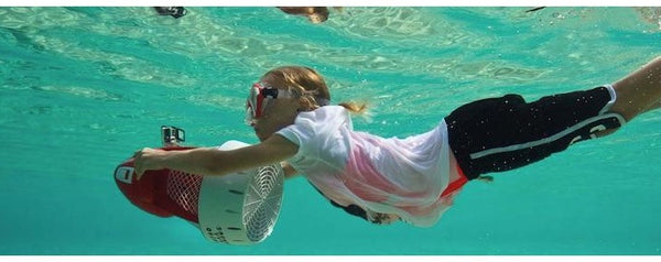 A young girl goes underwater with her Nautica Skipper Sea Scooter. You can see the GoPro camera mounted on top of the underwater scooter.