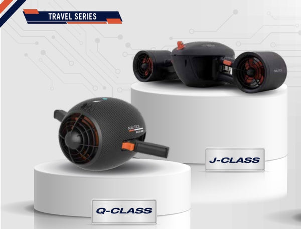 The 2 Nautica Travel Series Seascooters are pictured on staggered podiums. The Nautica Q-Class  sits in the front and the Nautica J-Class sits in the back. Both of the under water scooters have black bodies with small bits of orange highlights and a white logo.