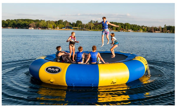 6 kids play on a Rave water trampoline for sale on a lake.
