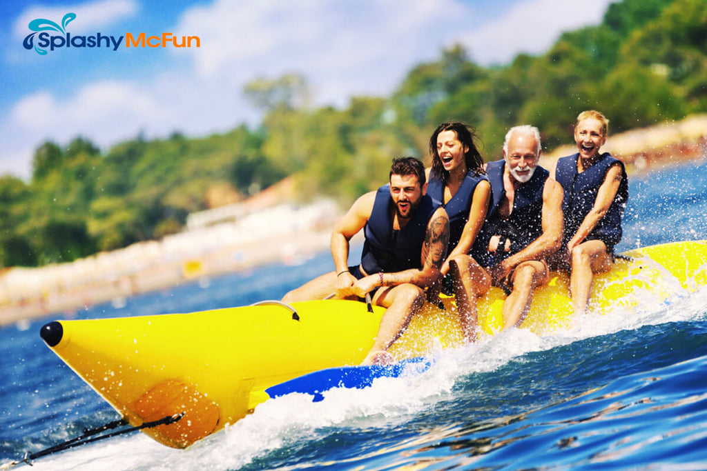 This is a Banana Tube with 4 people lined up, riding on it, holding onto the handles while being dragged by a speedboat on the water.