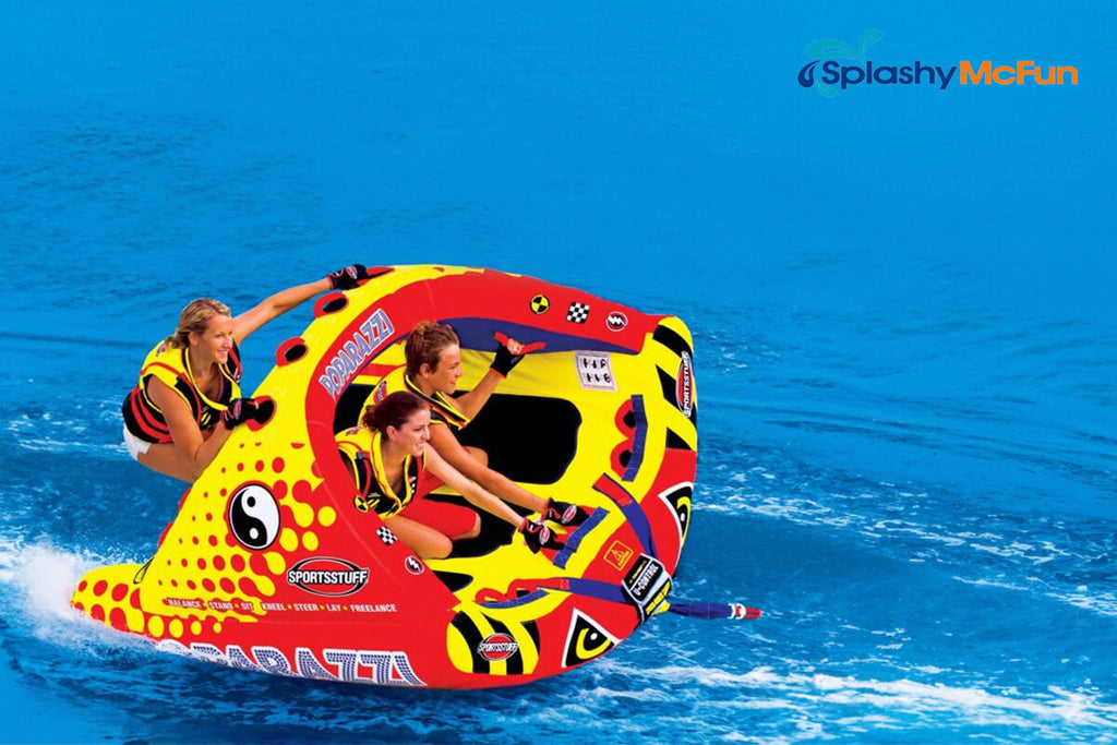 This is a Rocker Tube with 3 people on it in different positions, holding onto the handles while being dragged by a speedboat on the water.