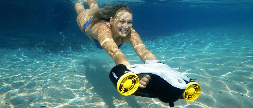 A girl swims with a dive propulsion vehicle.