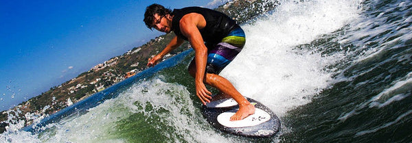 Wake Surfing image showing a man surfing on a wave made by a wake shaper.