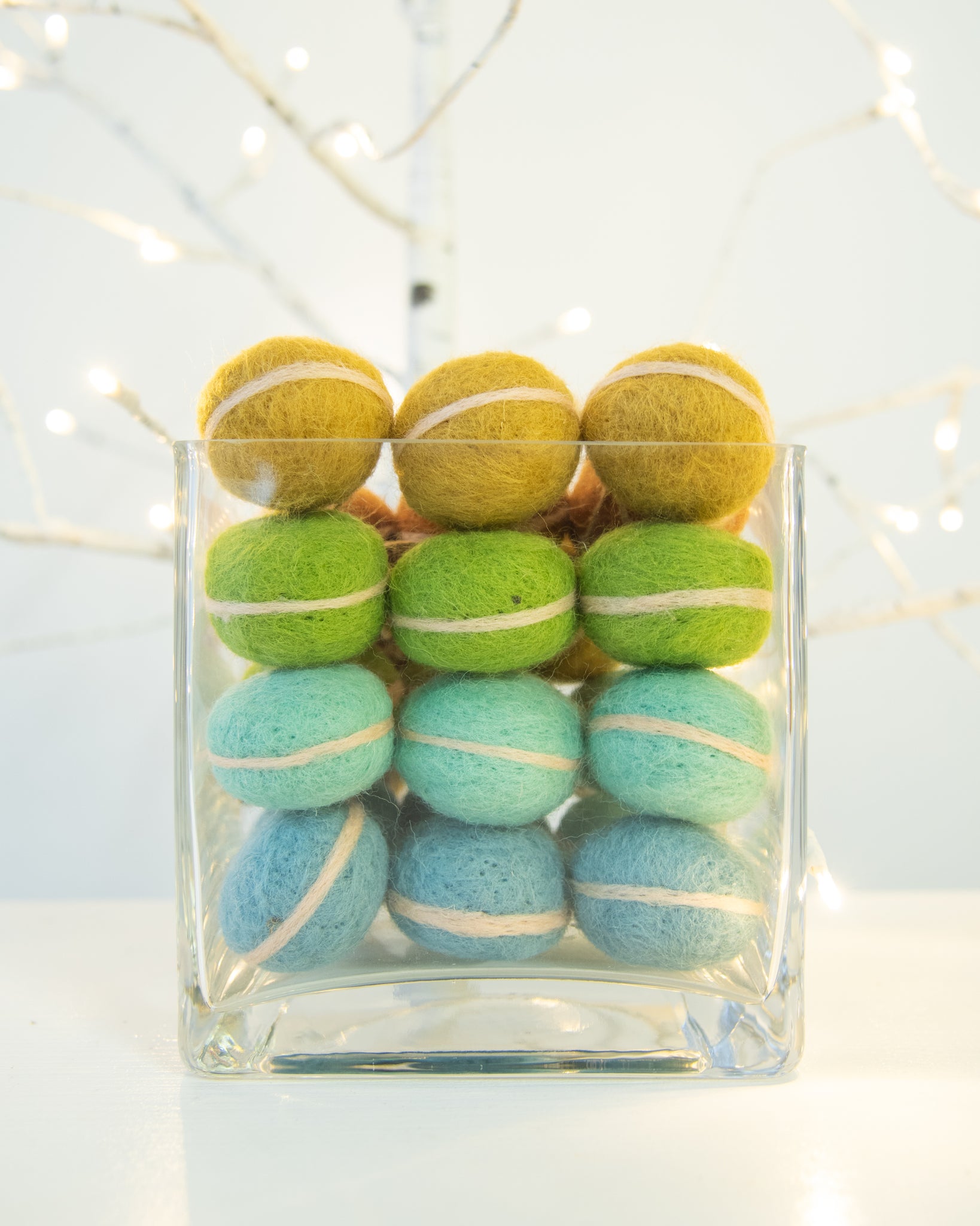 bowl full of colorful french macaron ornaments in front of white christmas lights