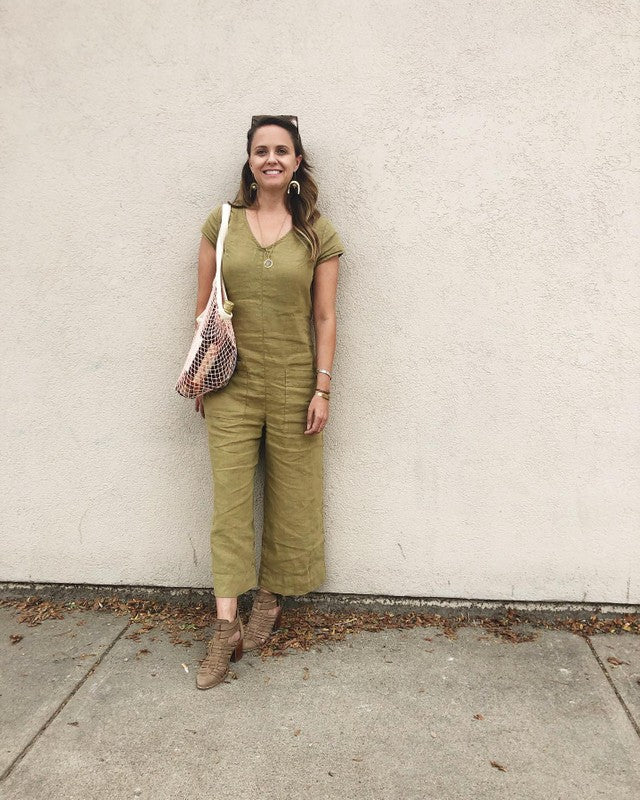 woman leaning against a wall wearing a green jumpsuit