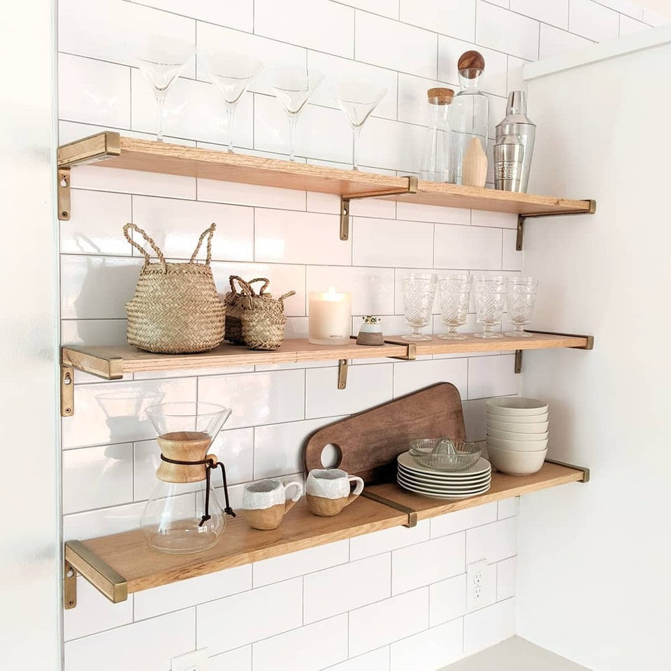 kitchen wall shelves with various glasses and wooden cutting boards. Three bamboo belly baskets together on middle shelf.
