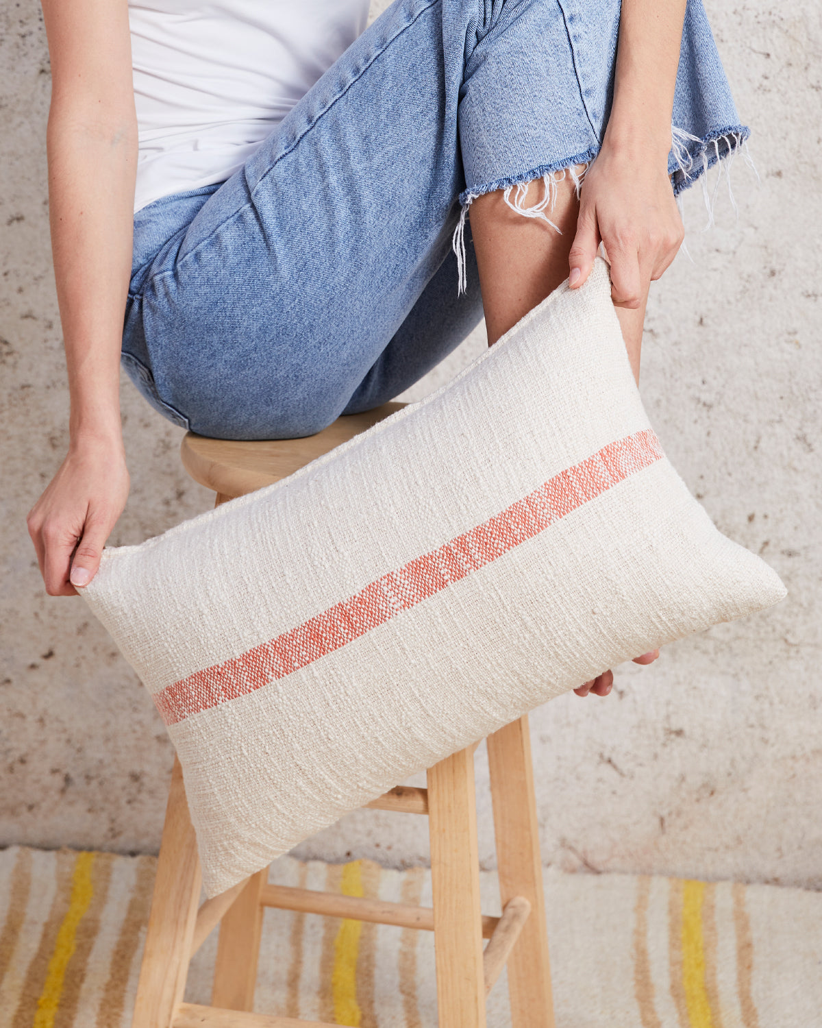 lumbar pillow with orange stripe in front of a stool