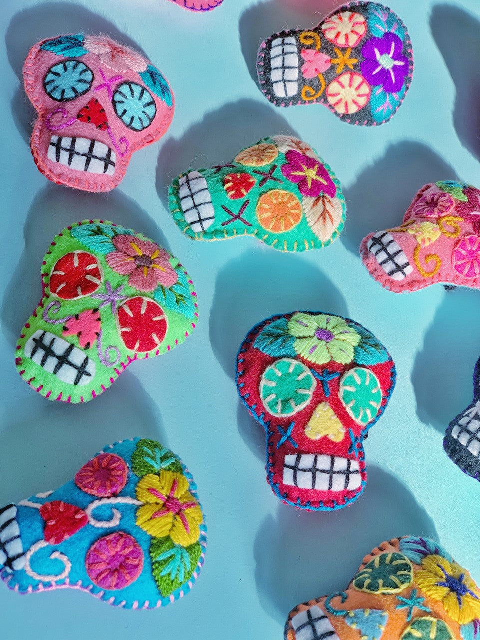 hand sewn sugar skull ornaments on a sky blue table